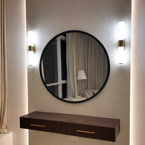 Round mirror with a dark frame on a wall with two wall lights and a wooden console below.