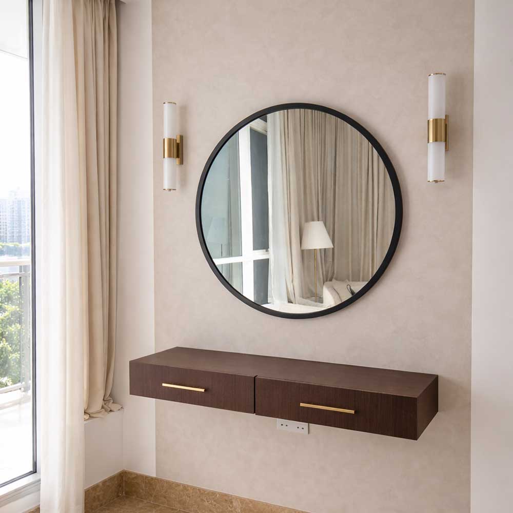 Round mirror with a wooden console table against a beige wall.