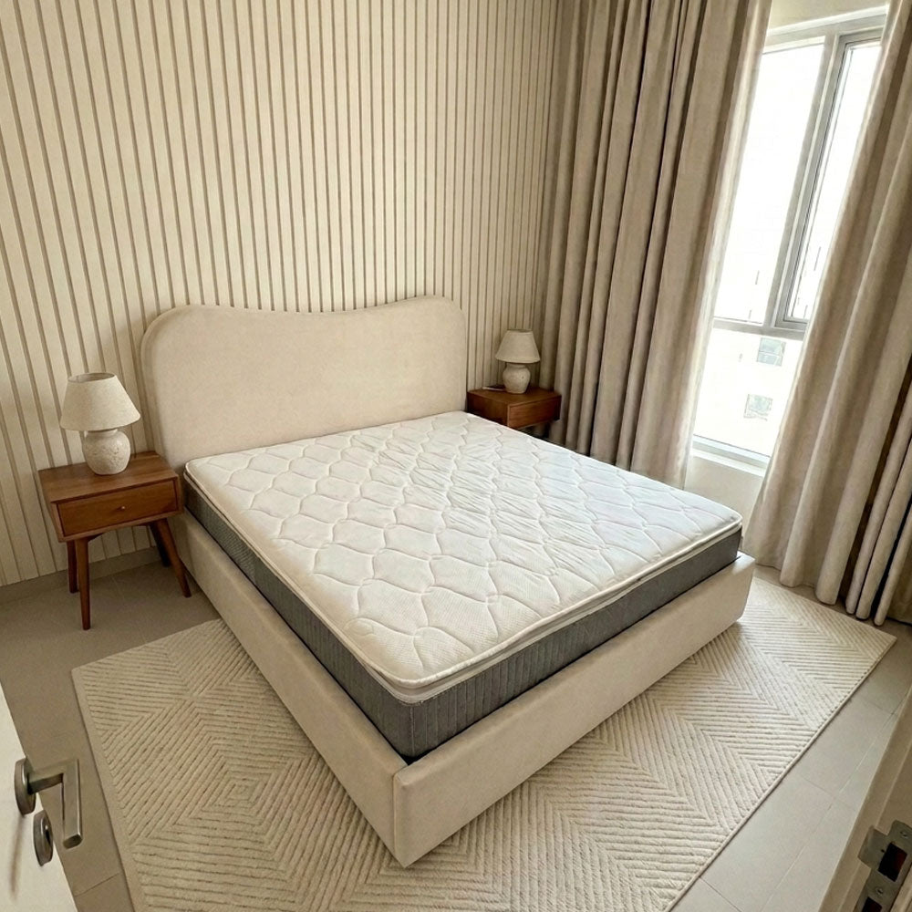 Bedroom with a bed featuring a mattress and two nightstands with lamps.