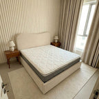 Bedroom with a bed featuring a mattress and two nightstands with lamps.