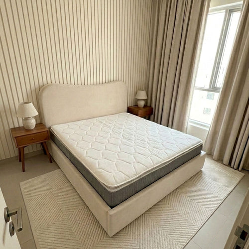 Bedroom with a bed featuring a mattress and two nightstands with lamps.