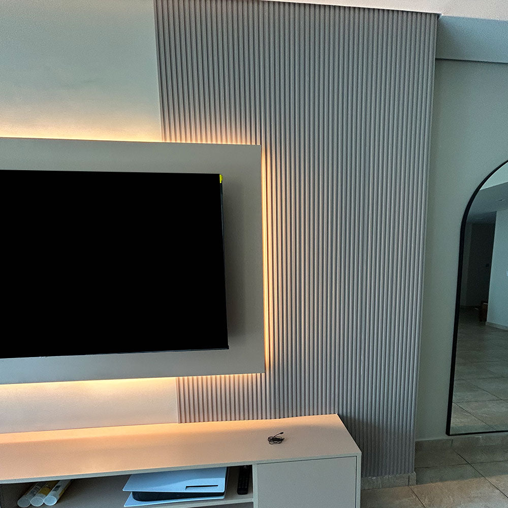 Modern living room with a television on a stand against a textured wall.