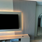 Modern living room with a television on a stand against a textured wall.