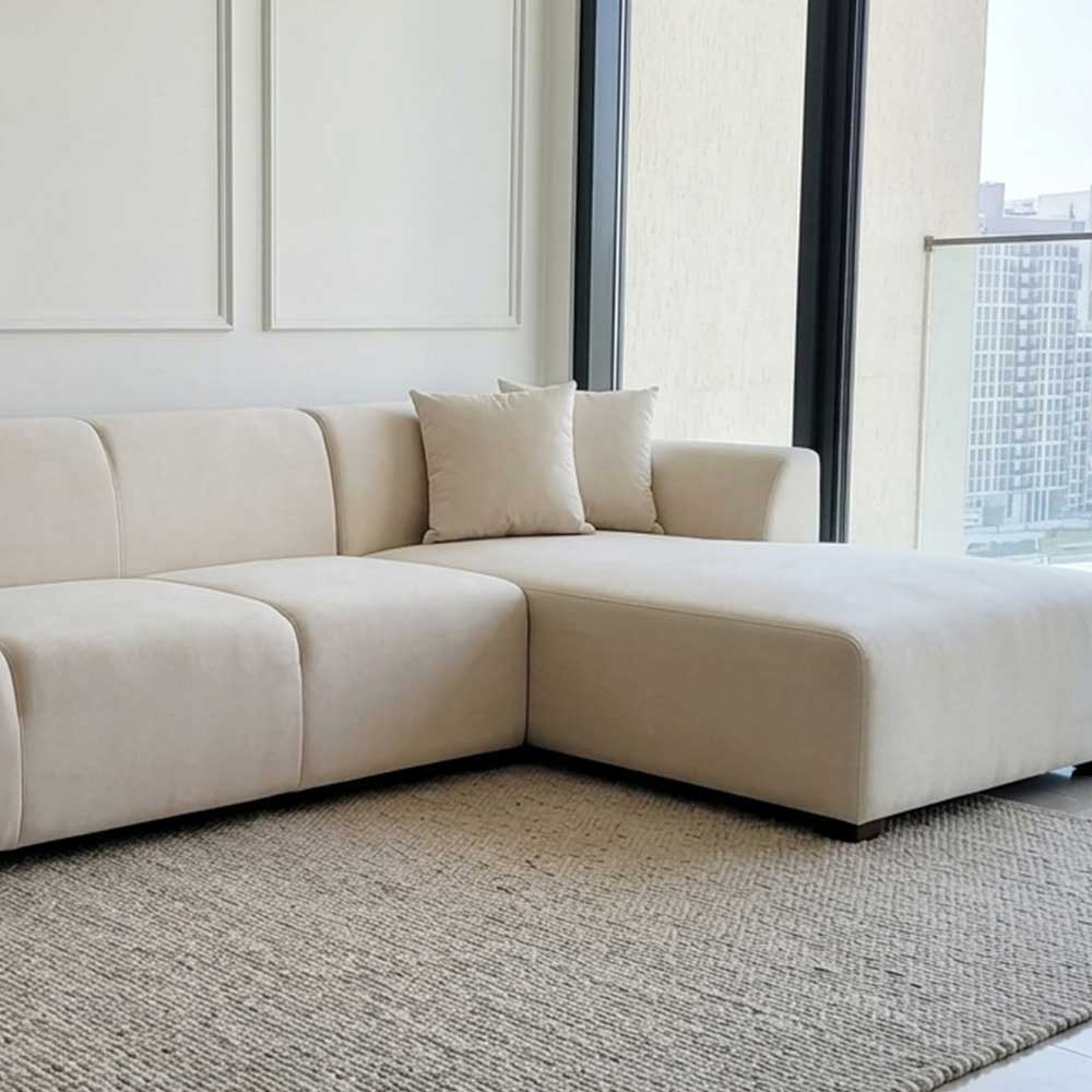 Large off-white L-shaped modular sectional sofa with plush cushions on a neutral rug in a modern living room