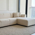 Large off-white L-shaped modular sectional sofa with plush cushions on a neutral rug in a modern living room