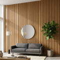 Modern living room with a gray sofa, round mirror, and wooden wall.